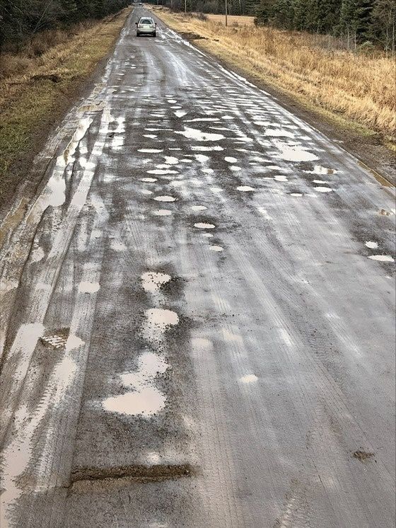 Vattensjuk grusväg med många potthål under vårens tjällossning